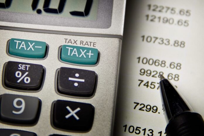 Calculator with tax keys beside a printed list of figures