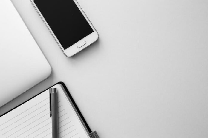 Smartphone lying on a desk next to a notebook