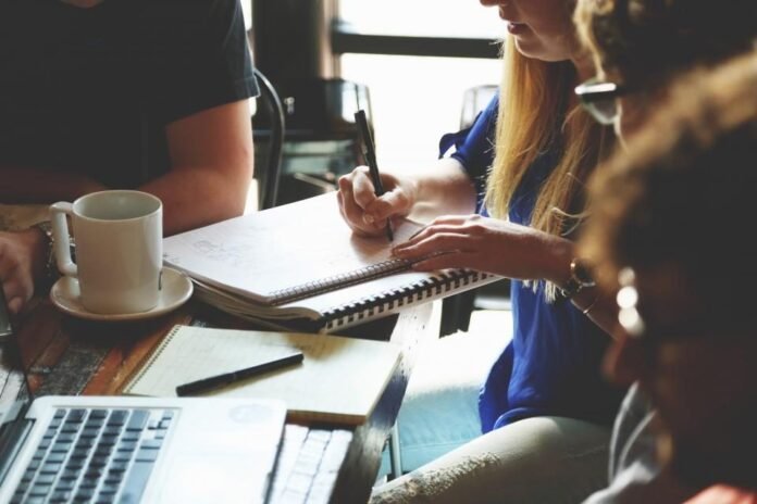 Startup team meeting around a table with laptops and notebooks