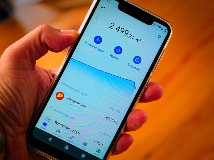 Hand holding a smartphone showing a banking app balance
