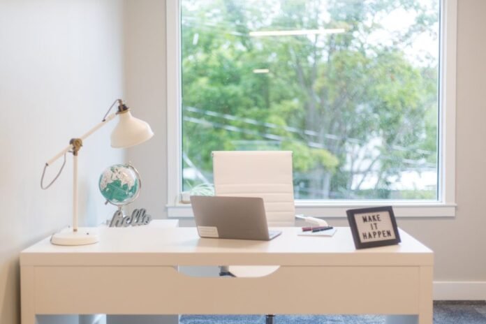 Bright home office desk with a laptop by the window